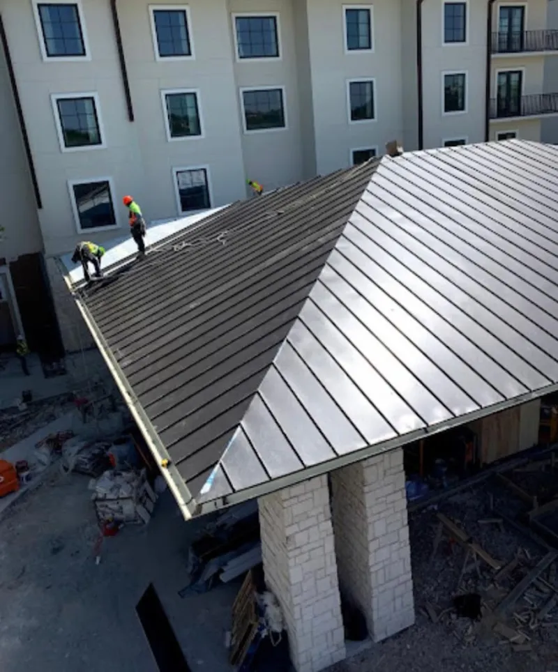 Crew installing standing seam metal roof panels on a commercial project in Sparta